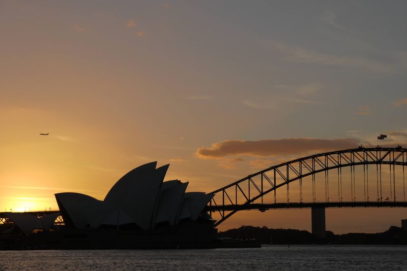 The sun setting over Sydney Opera House and Sydney Harbor Bridge