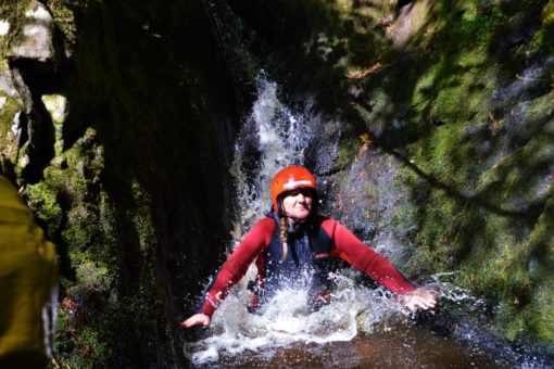 Sliding down a water chute on a canyoning trip with ACE Adventures, Scotland