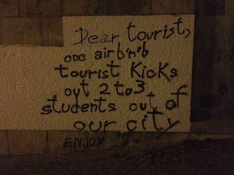 Painted sign in Coimbra complaining about tourists using Airbnb