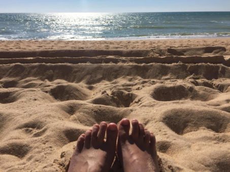 My feet in the sand down at the beach, contemplating our new site design